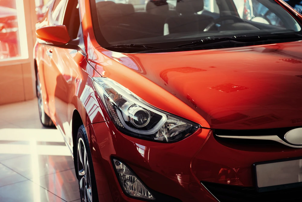 Intérieur d'un showroom automobile avec véhicule rouge métallisé exposé sous éclairage professionnel