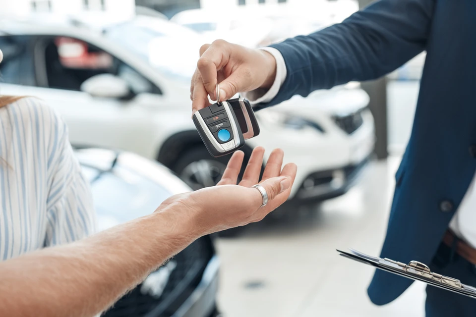 Scène de remise de clés automobiles dans un showroom de concessionnaire