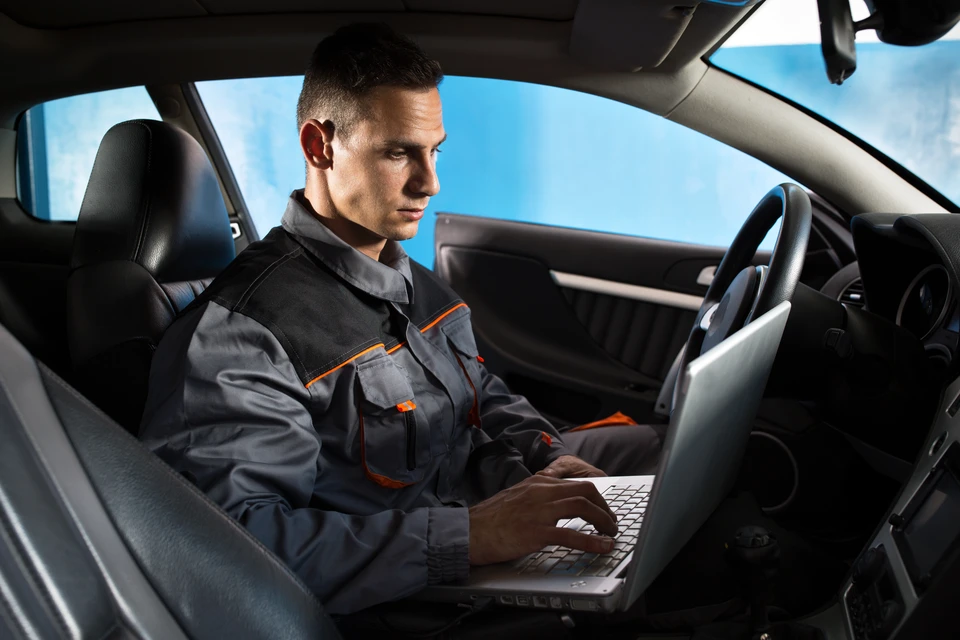 Scène d'atelier automobile high-tech montrant une berline BMW divisée par une ligne verticale orange