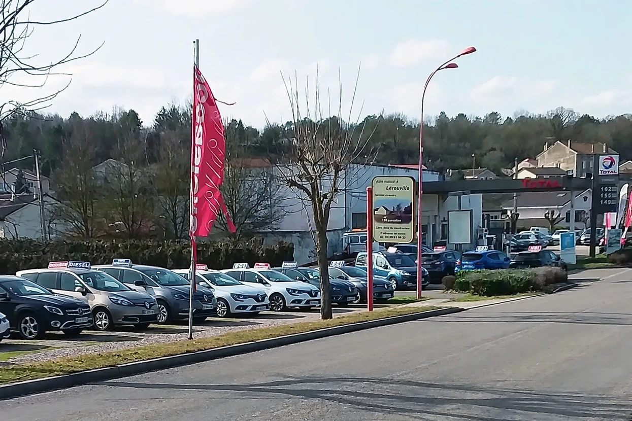 Scène en intérieur d'atelier automobile avec technicien effectuant nettoyage détaillé de carrosserie