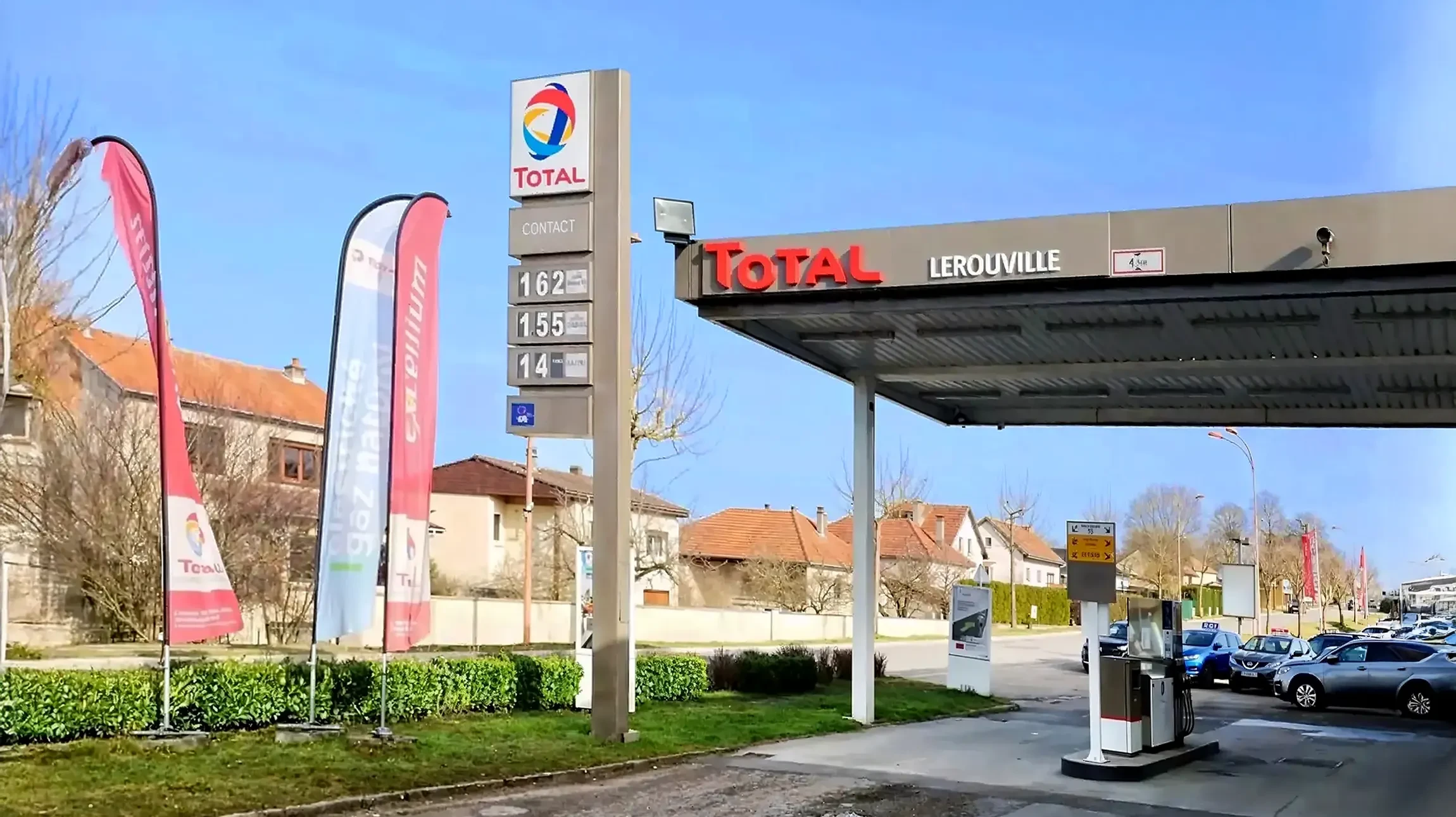 Intérieur d'atelier mécanique avec technicien en combinaison travaillant sous véhicule surélevé sur pont élévateur
